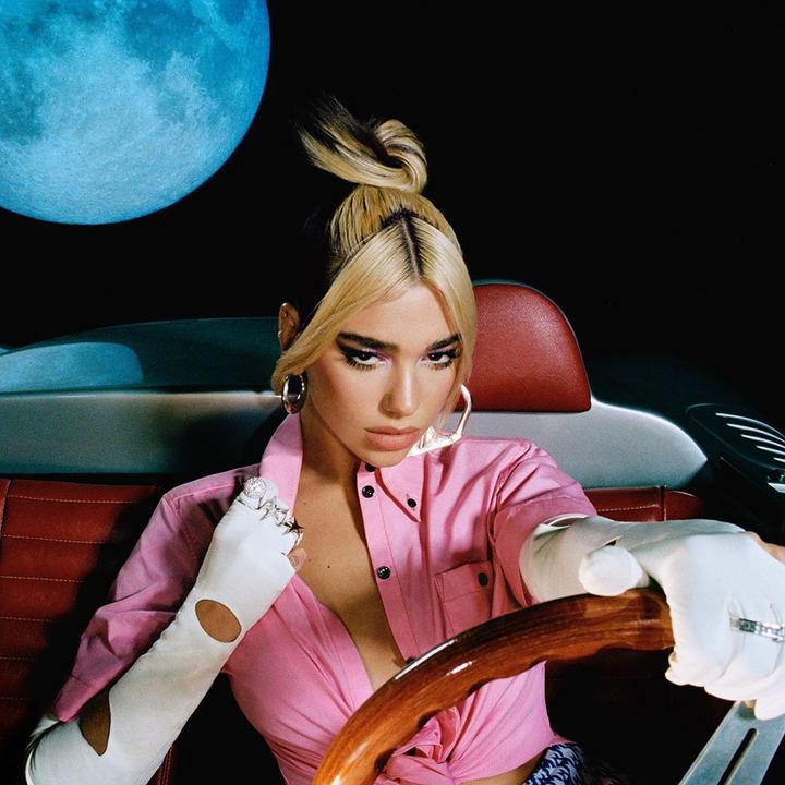 Dua Lipa Future Nostalgia album cover: Dua Lipa in a pink shirt and white gloves at the wheel of a car, a full moon behind her