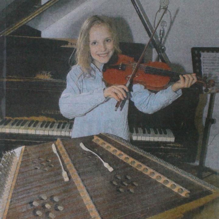 Joël Hainzl as a boy playing violin in front of a grand piano, his hackbrett and its hammers in the foreground, newspaper photo